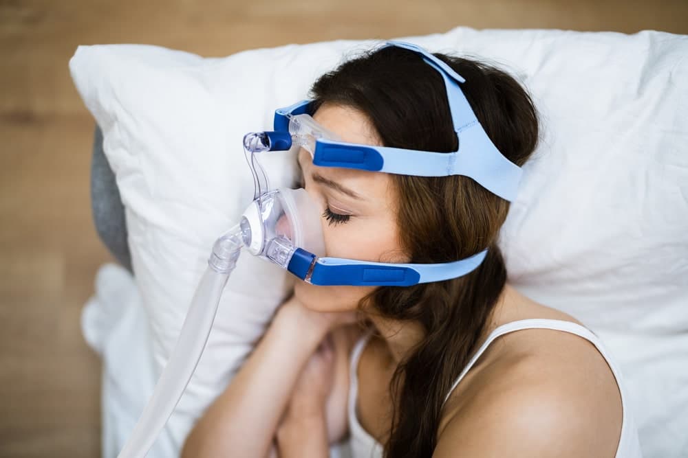 Woman sleeping with a CPAP machine for sleep apnea and AFib